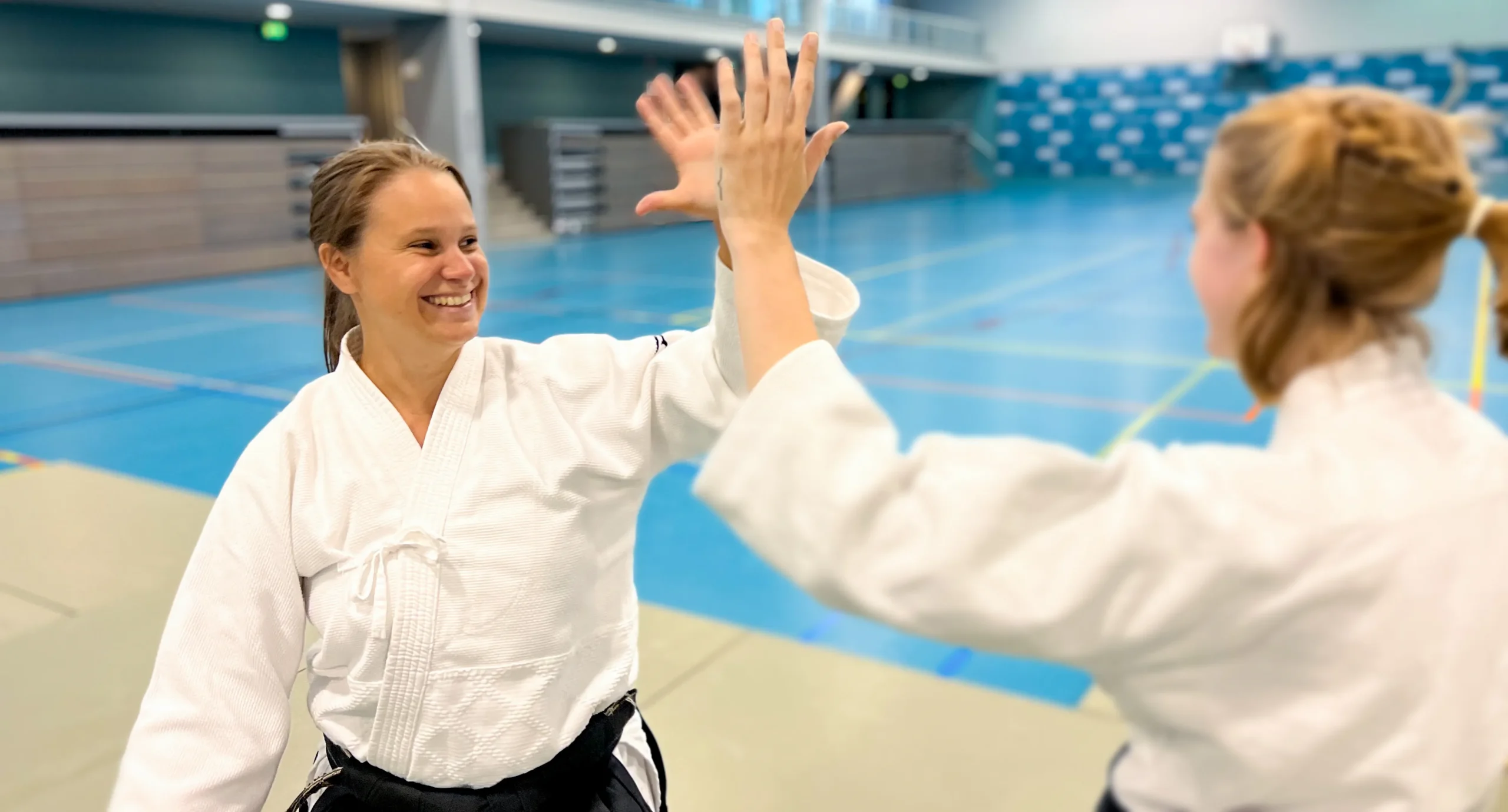 Sensei Anne 6th dan Aikikai Aikido teacher at Ando Dojo gives a gril a high five.
